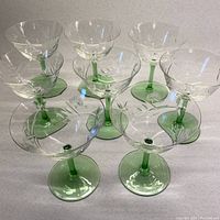 Top front view showing all eight crystal bowls arranged, highlighting the clear bowls and vibrant green stems and feet.