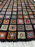 Full view of blanket laid flat showing granny square pattern and scalloped edging