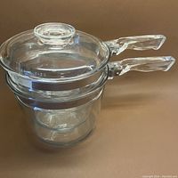 Side view of the vintage Pyrex double boiler stacked showing clear glass pots and stainless steel reinforced handles with glass lid on top.