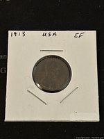 Front side of 1913 US Lincoln Penny showing Abraham Lincoln's profile and date '1913', held in white cardboard coin holder with annotations '1913 USA EF'.
