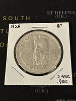 Reverse side of the 1958 Canadian silver dollar coin displaying eagle totem pole and inscriptions, in protective casing.