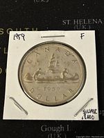 Front (reverse) side of 1959 Canadian silver 1 dollar coin showing a voyageur canoe design and date.