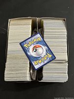 Two boxes full of Pokémon trading cards showing the classic blue backs with a Poké Ball design, cards are packed tightly inside Ultra PRO card sleeve boxes.