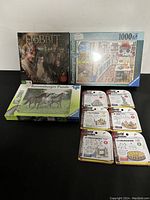 Nine assorted puzzles and a board game arranged in a group, including Ravensburger puzzles and 'The Hobbit' game.