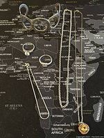 Full view of all items laid out on a map background: two necklaces, three rings, one bracelet, and one wide bangle bracelet, all sterling silver stamped 925.