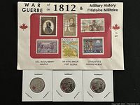 Photo of 6 Canadian postage stamps on card with text referencing War of 1812 and related historical figures along with 3 silver-toned coins beneath the card.