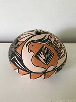 Front view showing the bird motif and geometric patterns on the pottery.