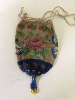 Full view of antique beaded drawstring bag showing floral beadwork and tassel.