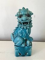 Front view of the blue glazed foo dog showing detailed facial features, open mouth, and base with cut-out design.