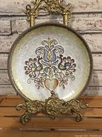 Front view of the antique German hand-painted ceramic wall plate showing the full floral and heart motif design with a textured grayish background and dark rim.