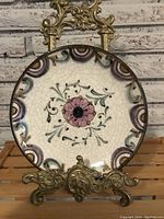 Front full view of the antique round ceramic wall plate showing floral hand-painted design and crackle glaze.