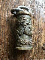 Front side showing one dragon with a detailed face, scales, and claws on a carved soapstone cylindrical lock.