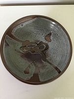 Top view of the mid century Dexter pottery bowl showing abstract interior glaze in muted green, brown, and purple tones