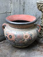 Full side view of large round hand painted ceramic outdoor pot with floral designs and two handles.
