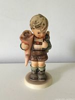 Front view of the Little Scholar Hummel porcelain figurine, showing the young boy holding a rolled-up school cone and a book.