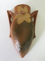 Front view of brown Roseville Pottery planter with dual handles and floral design