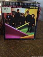 Front cover of 'Wrap It!' LP by Doug And The Slugs showing six band members and colorful fabric background.
