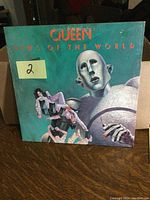 Front cover image of Queen 'News of the World' LP showing robot holding humans.