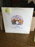 Front cover of Queen A Night at the Opera LP album. White cover with colorful artwork featuring a phoenix and faces.