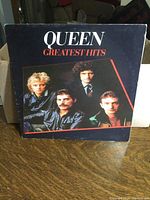 Front cover photo showing Queen Greatest Hits album artwork and band photo.