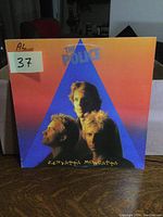Front cover of The Police Zenyatta Mondatta vinyl LP showing band member portraits in a blue triangle on an orange gradient background.