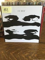 Front cover of U2 Boy vinyl LP with stylized black silhouettes on white background.