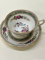 Side angle showing teacup inside the saucer, displaying floral decoration and gold accents.
