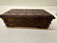 Side view showing geometric and spiral carvings on the box with interlocking corner joints.