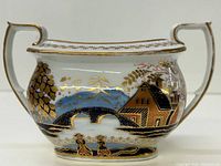 Front view of the sugar bowl showing detailed hand painted scenic design with gold gilt accents.