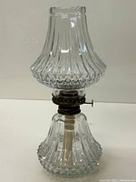 Full view of the vintage oil lamp showing diamond cut clear glass chimney and base, with brass burner and cut wick.