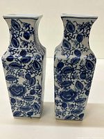 Pair of square blue and white Asian style vases shown from front with detailed floral patterns on white ceramic.