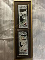 Photo of the full pair of framed Chinese stamped papercut artworks displayed vertically one above the other in a single frame with a brown and gold border.