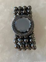 Top view showing the bracelet's three-strand black beads and a large central faceted black gem encircled by smaller beads.