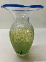 Front view of the tulip-shaped vase, showing clear glass with green-blue spatter and blue rim.