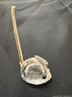 Front side view of the clear crystal Swarovski mini mouse figurine on black fabric background.