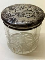 Full view of the vintage cut glass jar with focus on the embossed silver lid showing angel faces.