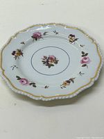 Full view of the antique hand-painted decorative porcelain plate showing scalloped edges, floral designs and gold trim