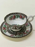 Top view of a Coalport Indian Tree teacup on matching saucer showing intricate floral and bird designs and brown geometric border pattern.