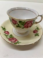 Tea cup and saucer set viewed from top and angle to show rose pattern details and gold trimming.