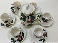 Teapot surrounded by 6 cups and saucers, showing the overall set layout and cherry design.