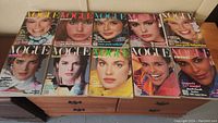 Full view of 10 Vogue magazines laid out in two rows showing cover images of various 1980s fashion models