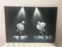 Full front view of the rectangular black relief artwork featuring two ice hockey players in action under spotlight effects.