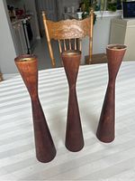 Three wooden candle holders arranged upright on a striped tablecloth, showing overall shape and finish.