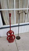 Full view of red coffee grinder lamp and brass-tone bridge lamp side by side