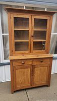 Front view of entire two-tier pine cupboard showing glass doors, drawers and lower cabinet