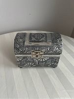 Photo of closed embossed metal jewelry box showing floral pattern and latch