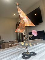 Full view of mid century copper brutalist windsorfer sculpture with triangular copper sail and stylized pink element.