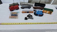 Full lot overview showing multiple train cars, track pieces, power pack, couplers, and model building on white table