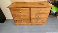Front view of the six drawer pine dresser showing natural wood, white knobs, and condition of drawers.
