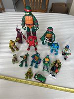 Wide view of all action figures arranged on table with measuring tape for scale